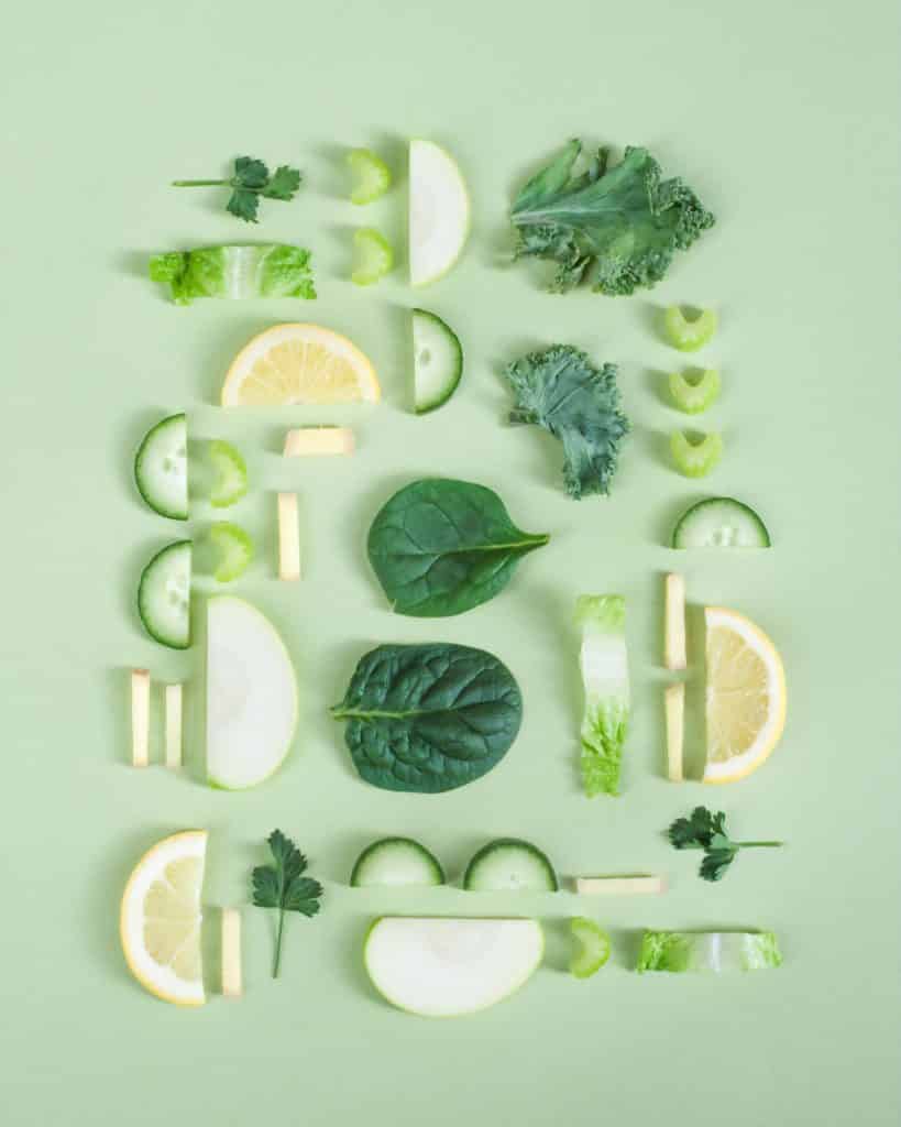different green fruits and vegetables that are cut up and layed out in an aesthetically appealing way.