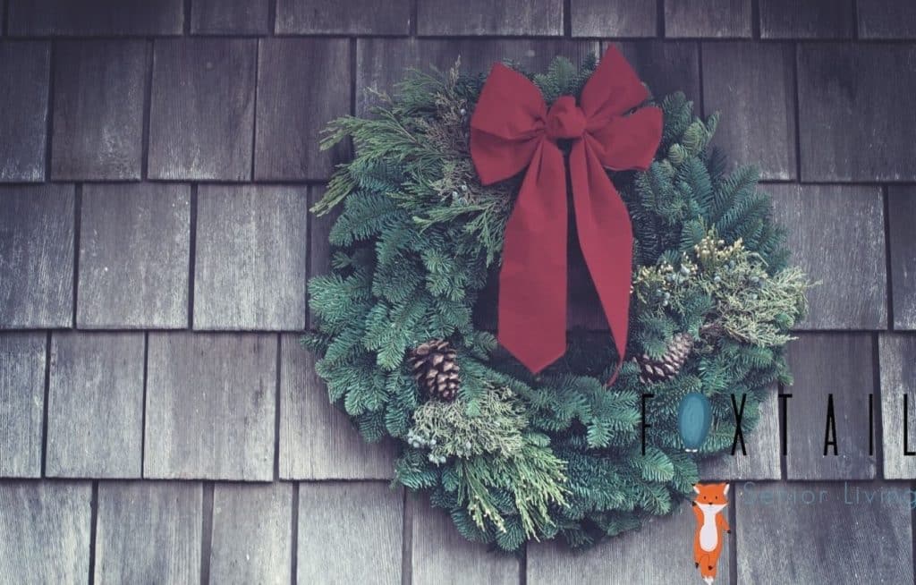 Christmas wreath with a red bow hanging on a shingle wall