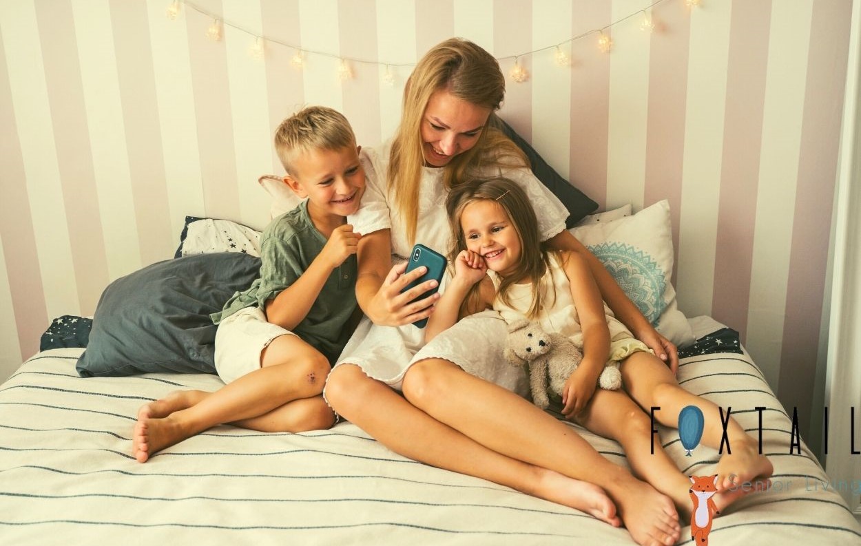 Mom, son, and daughter video calling family on a bed