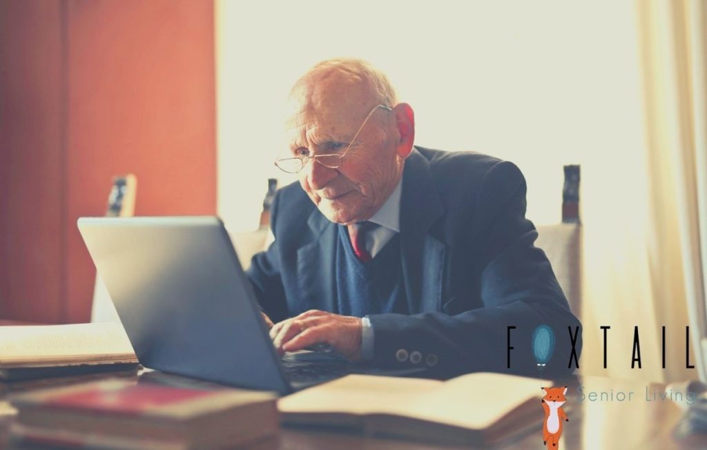 Senior man with glasses and a suit working on his computer