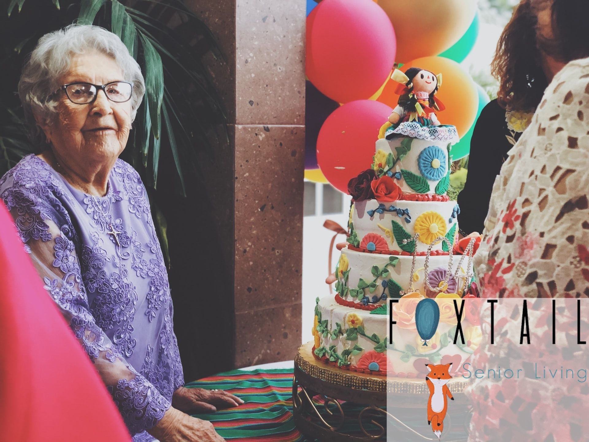 elderly woman wearing purple with a cake in front of her